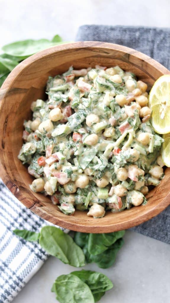 A beautiful bowl of vegan chickpea Tahini salad, mixing chickpeas with lettuce and tomatoes with the unique Tahini dressing.