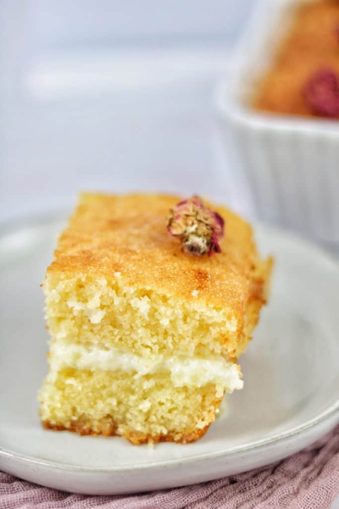 easy basbousa cake filled with cream, drizzled with attar syrup, and garnished with rosebuds