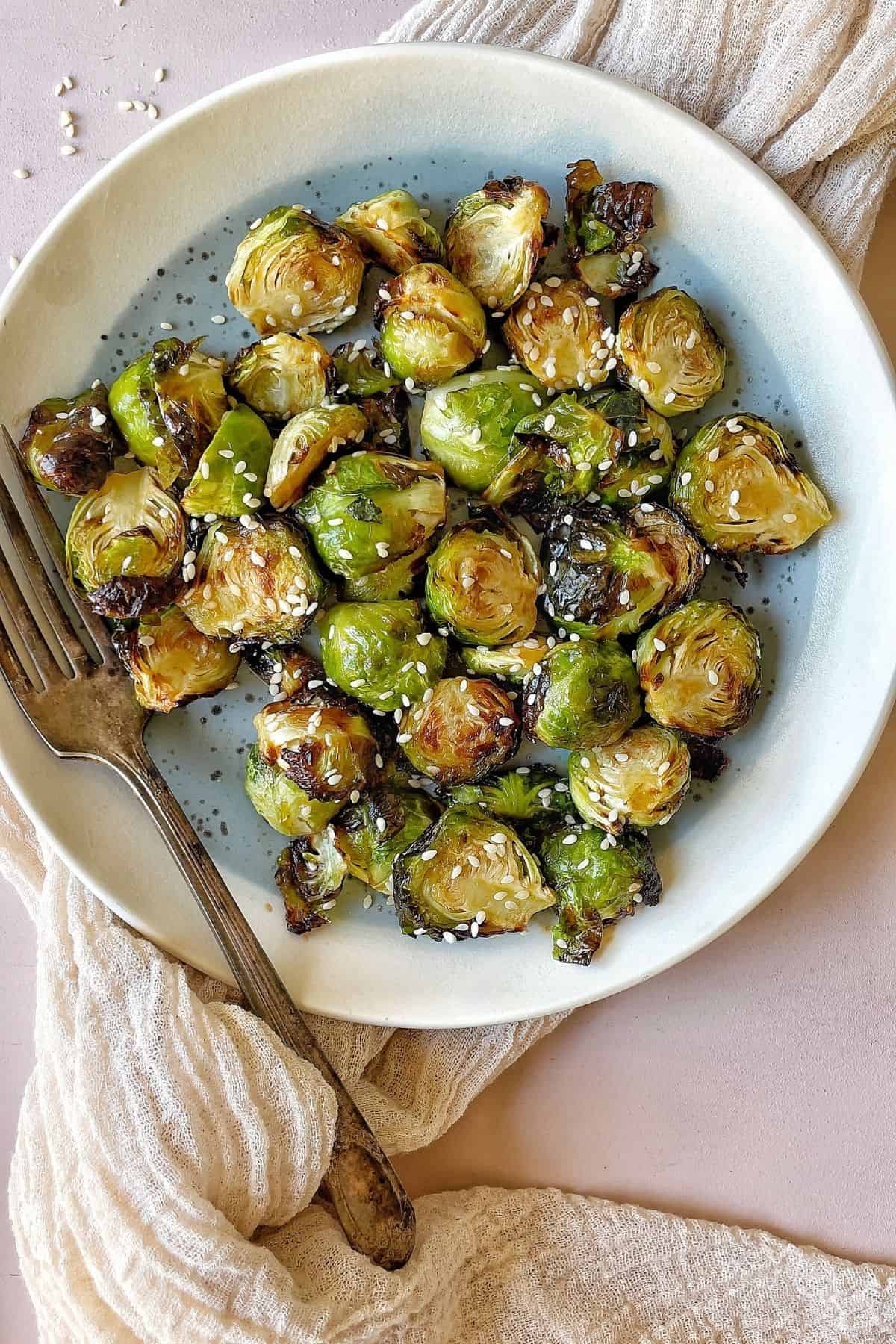 These Brussel sprouts are coated in a flavorful glaze and roasted until crisp and browned. Then they are topped with a generous amount of sesame seeds.