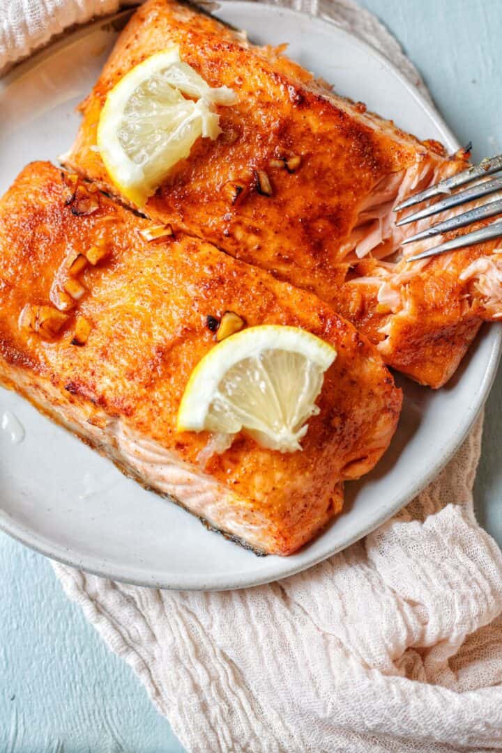 Two perfectly air fryer salmon fillets glazed with honey, soy sauce, and other seasoning to create a sticky sweet sauce on the salmon skin.