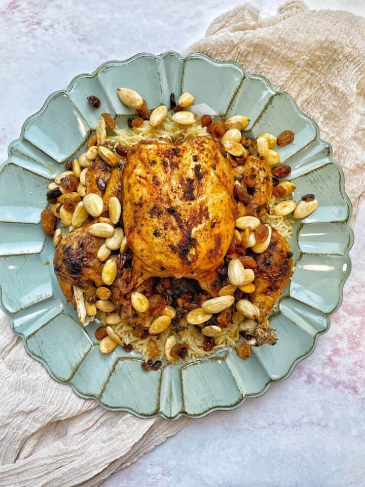 This instant pot whole chicken and rice recipe present a golden  crunchy chicken over a fluffy serving of rice, with a drizzle of almonds and raisins 