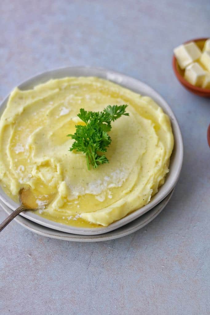warm creamy mashed potatoes topped with green soft parsley and melted garnish butter ready to be served