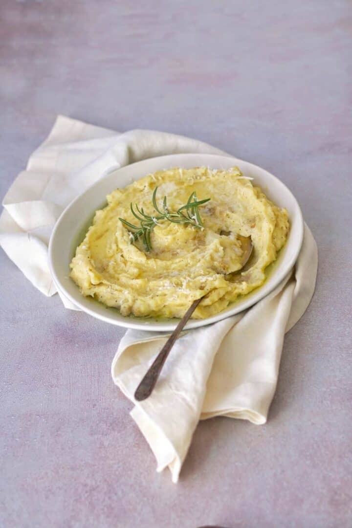 a yummy mashed potatoes plate served warm with extra parmesan cheese on the top, olive oil, and rosemary 