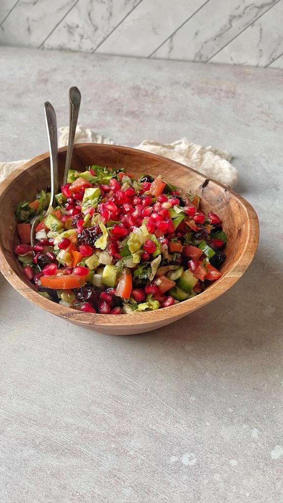A multicolor salad made from veggies, pomegranate seeds, dried sweetened cranberries, and pomegranate molasses.