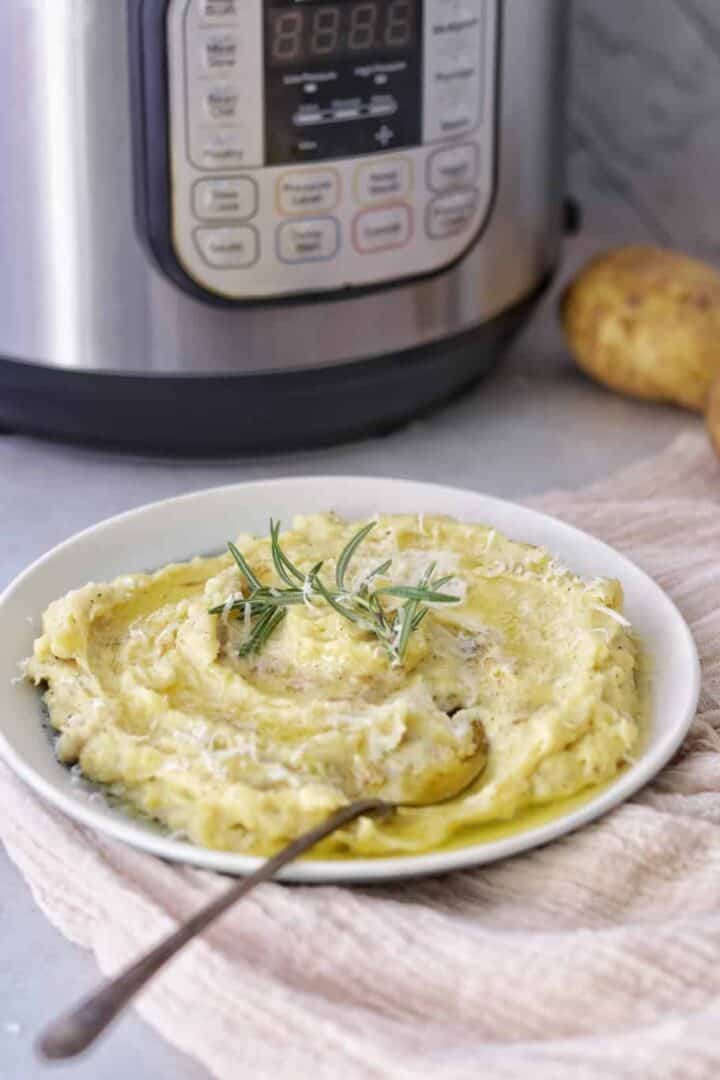 instant pot mashed potatoes made with love and ready to be served with olive oil, rosemary fresh herb, and extra parmesan cheese on the top