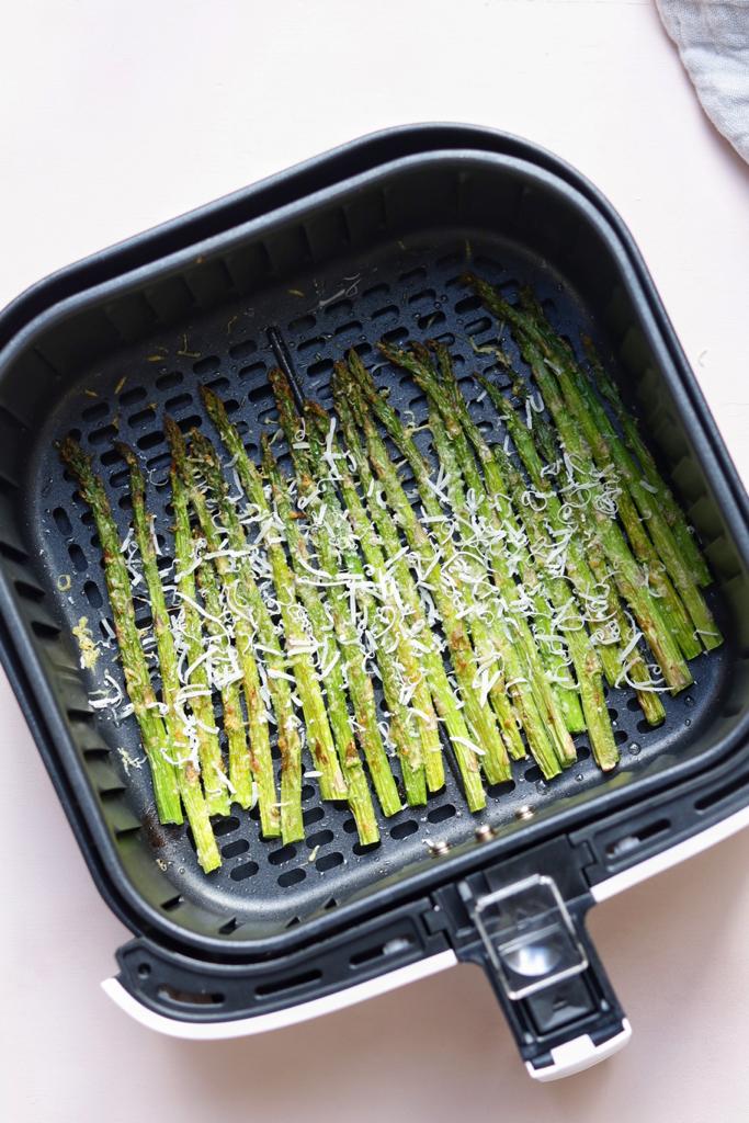 Asparagus set on a single layer in the air fryer after seasoning it with garlic powder, onion powder and olive oil. Cheese is sprinkled on top to get a mouthwatering taste.