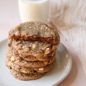 Brown butter salted chocolate cookies with chocolate chips served with a cup of cold milk.