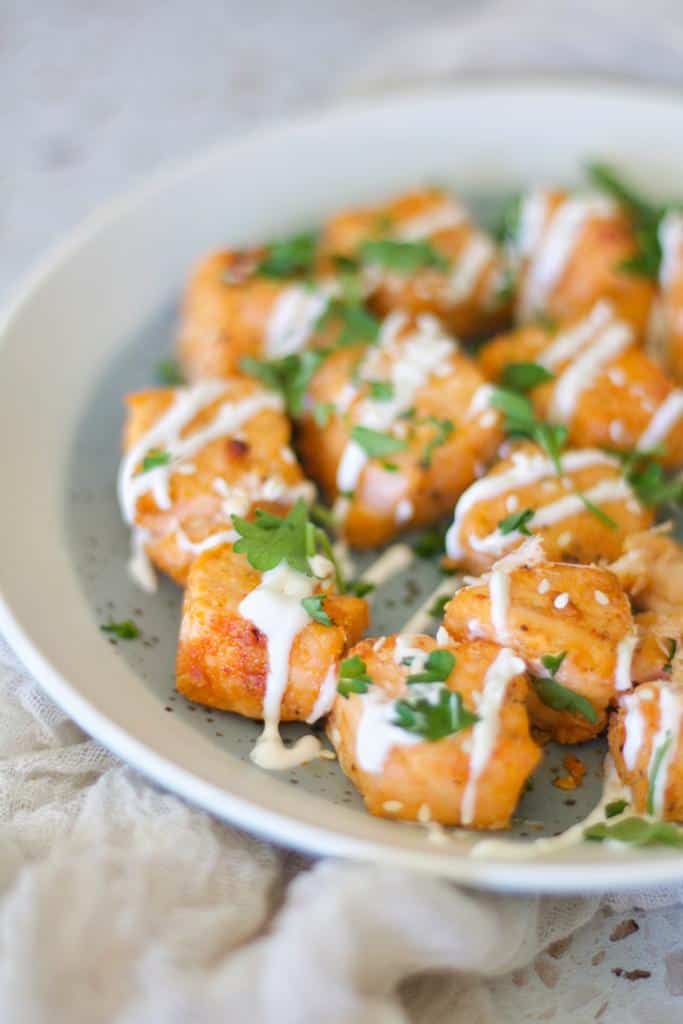 keto air fryer salmon nuggets on a plate with greens and sauce