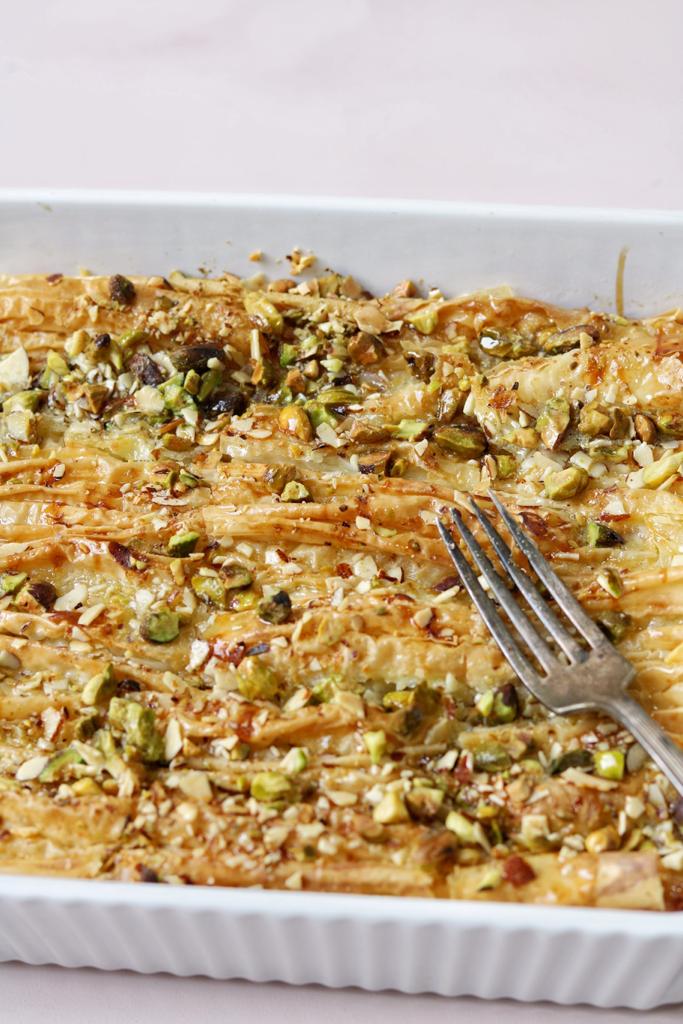 Mesh Om Ali in a baking dish soaked with milk and simple syrup and garnished with pistachios, The perfect dessert for family and friends.