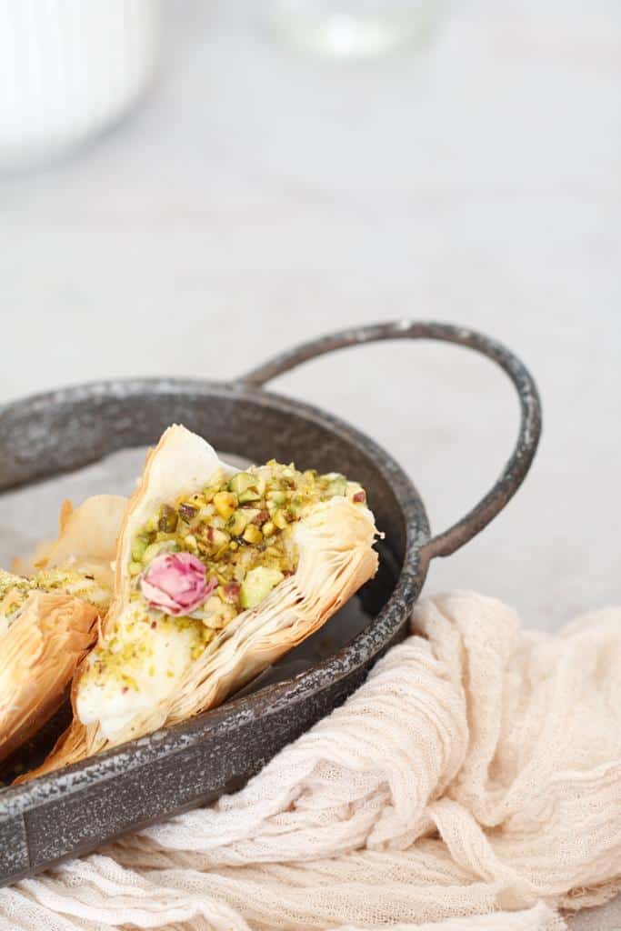 so delicious Shaabiyat, filled with Ashta, garnished with crushed pistachios, drizzled with simple syrup, and topped with rosebuds 