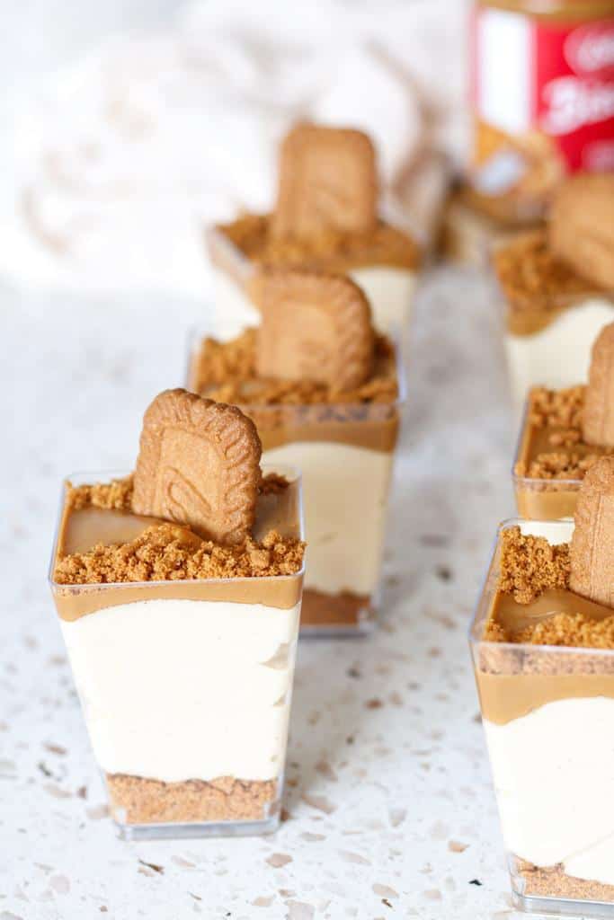Biscoff cheesecake cups with a thick crumb base, a luxurious cheesecake layer, and more biscoff spread and cookies on top.
