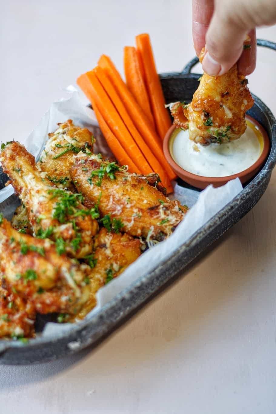 crispy chicken wings dipped in a hearty sauce garnished with finely chopped fresh parsley and served with roasted carrots