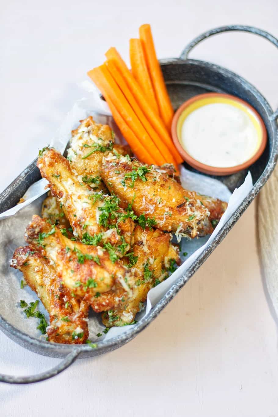 crunchy chicken wings garnished with finely chopped fresh parsley and served with garlic Parmesan sauce and roasted carrots