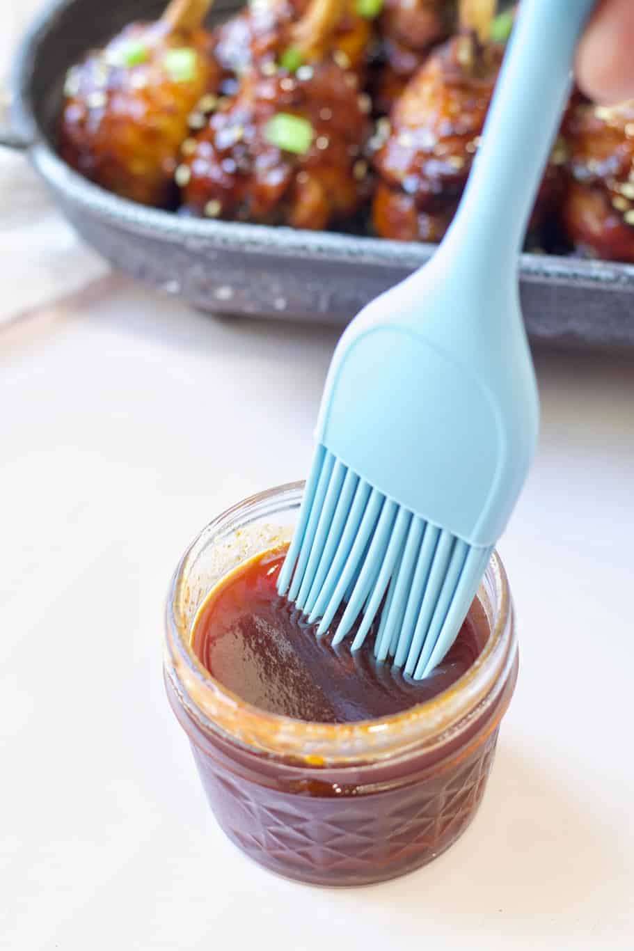 a blue brush dipped in the honey sriracha sauce