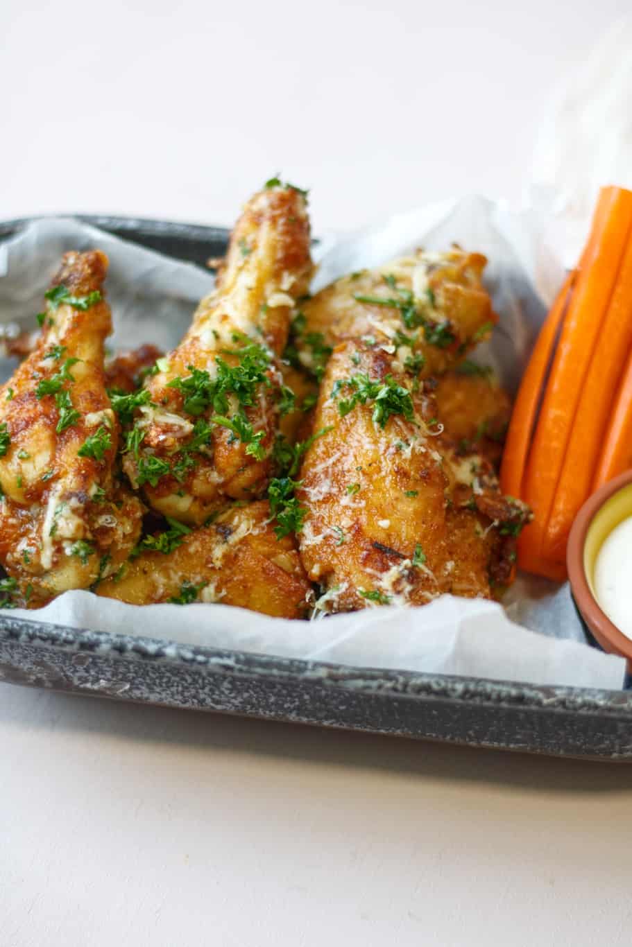 so crispy skin on chicken wings and so juicy tender inside meat garnished with finely chopped fresh parsley and served with roasted carrots 