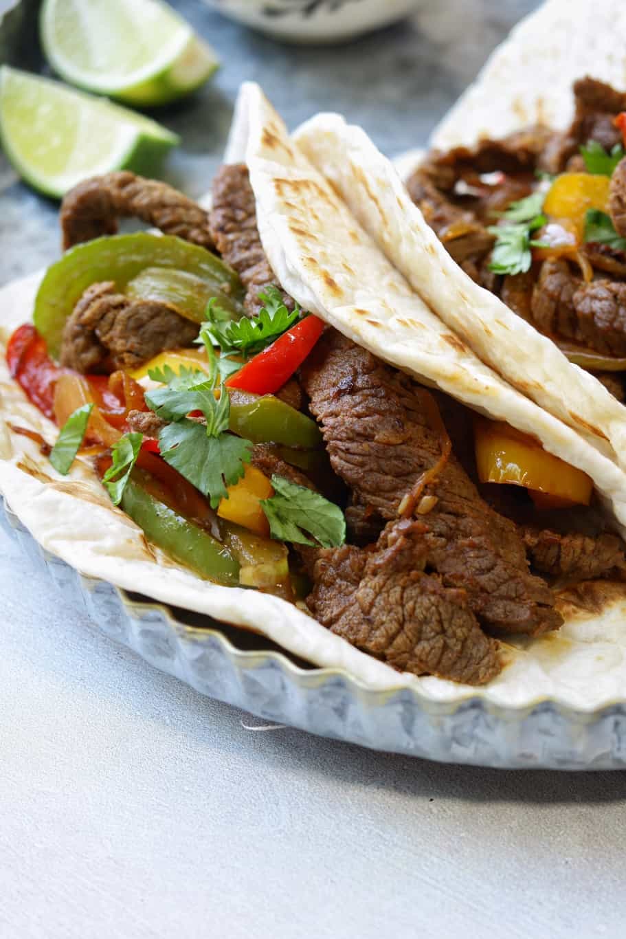 a so delicious warm beef fajita tortillas filled with cooked skirt steak, onions, and bell peppers sprinkled with chopped cilantro