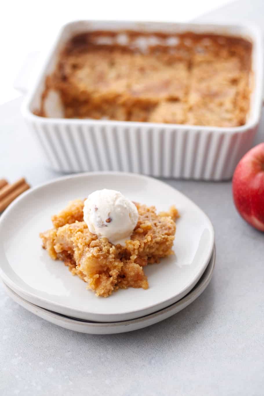 apple dump cake in a baking dish and a piece of apple cobbler topped with a scoop of ice cream