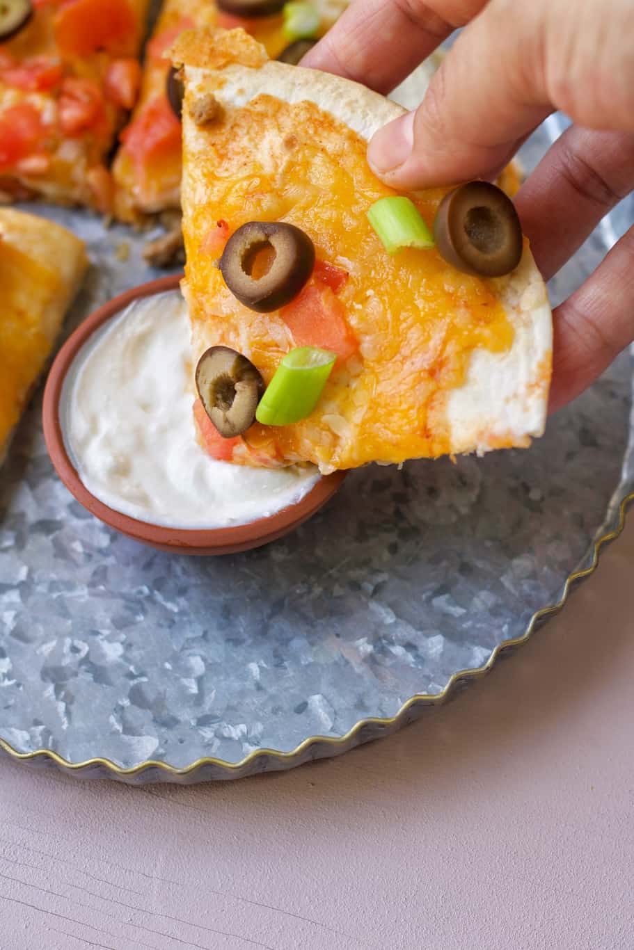 a slice of keto mexican pizza dipped in sour cream