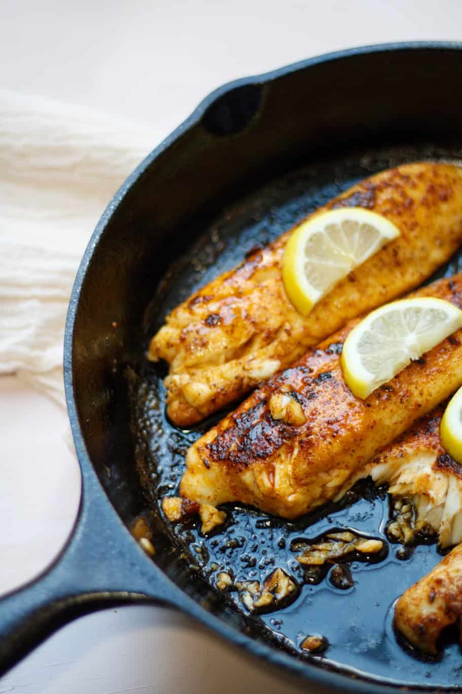 Tender and juicy lemon butter tilapia fillets in a cast iron skillet