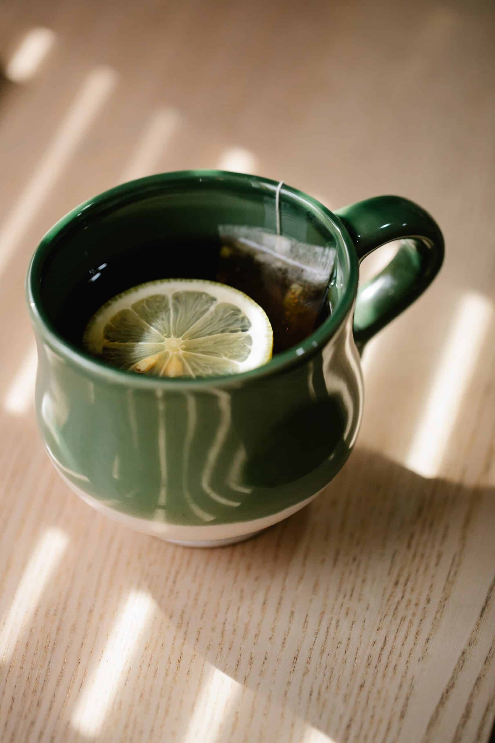 a hot cup of green tea bag with a slice of lemon