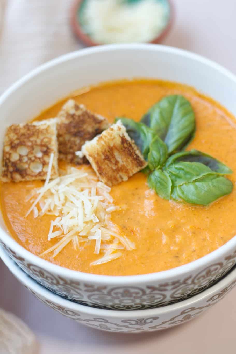 This instant pot tomato basil soup is served with fresh basil leaves, grated parmesan cheese, and crunch croutons on the top.