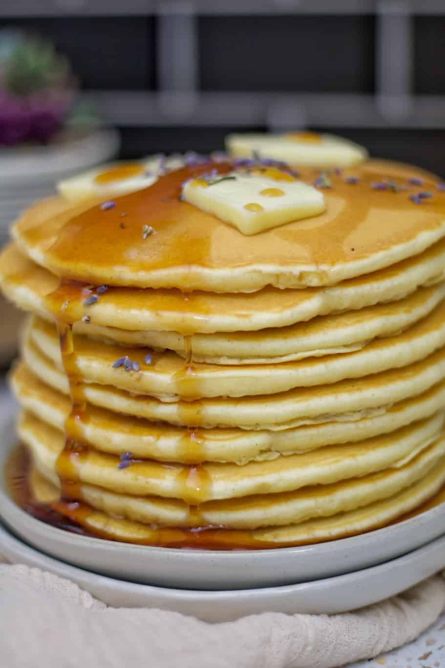 golden brown pancakes stacked above each other with some melted butter and maple syrup on top