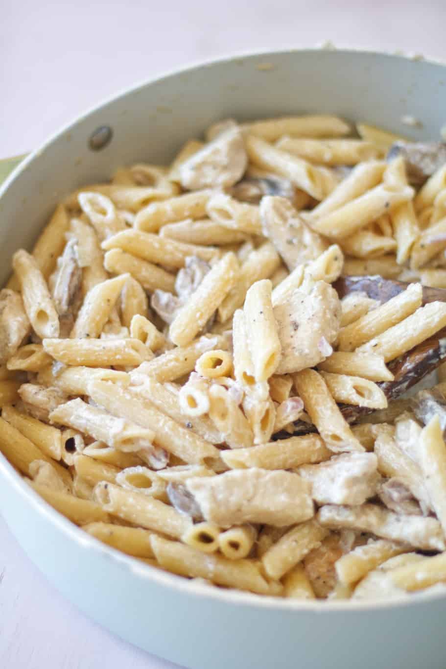 a bowl of penne pasta with a cheesy creamy sauce and mushrooms and onions which makes a great dinner
