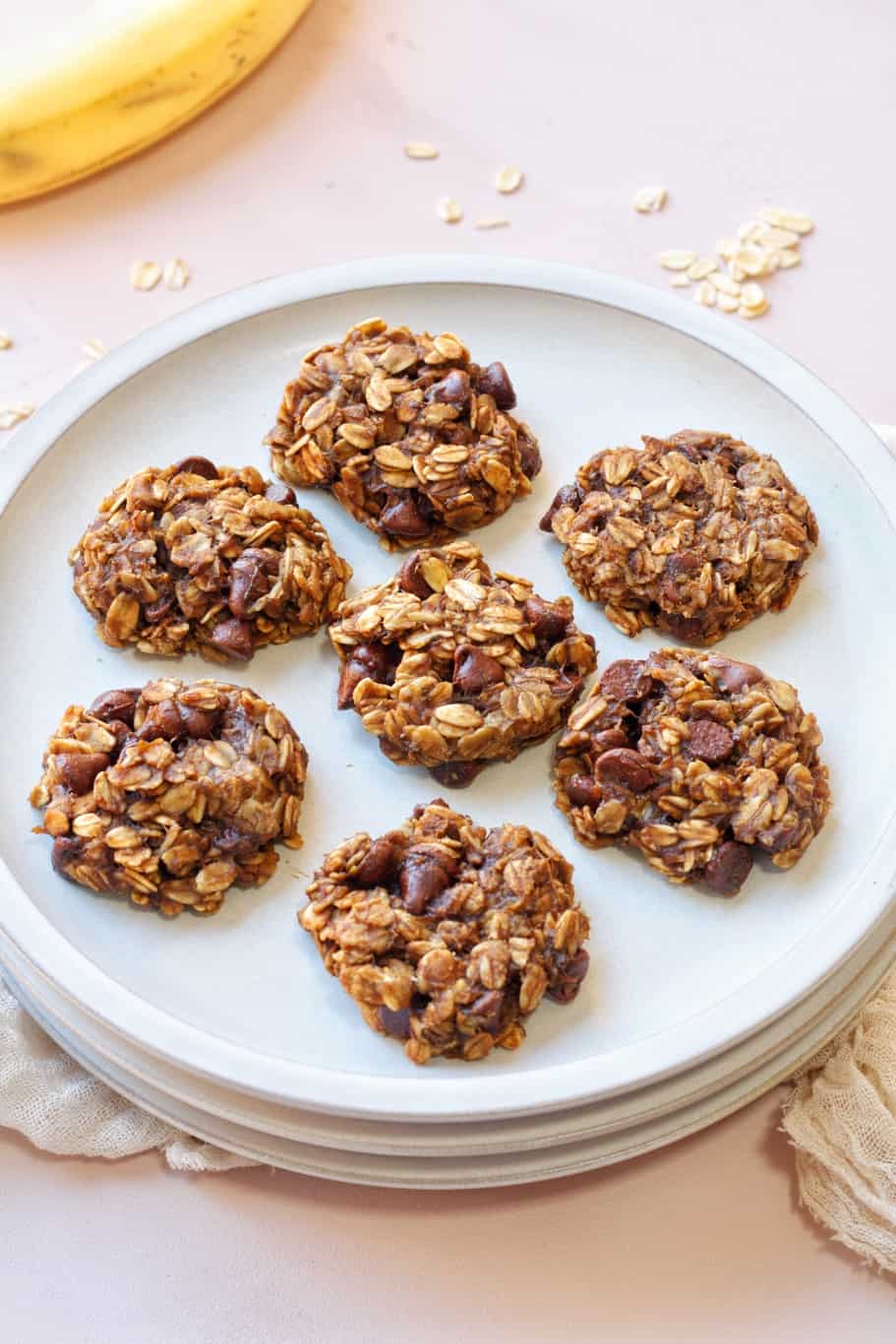 7 pieces of perfectly baked and golden brown banana oatmeal cookies on a white serving plate. 