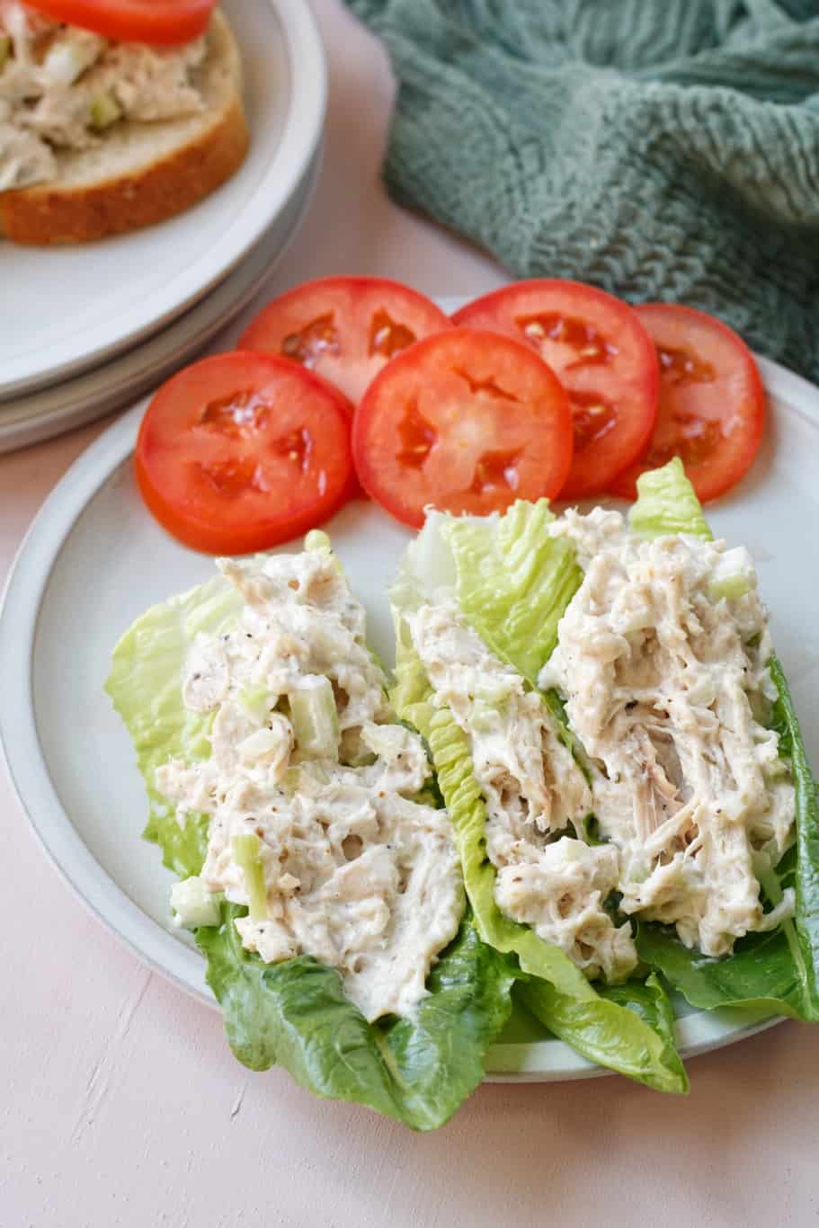 creamy zoe's chicken salad made up of shredded cooked chicken, chopped celery, mayo, salt, and black pepper served on a bed of fresh lettuce alongside tomatoes