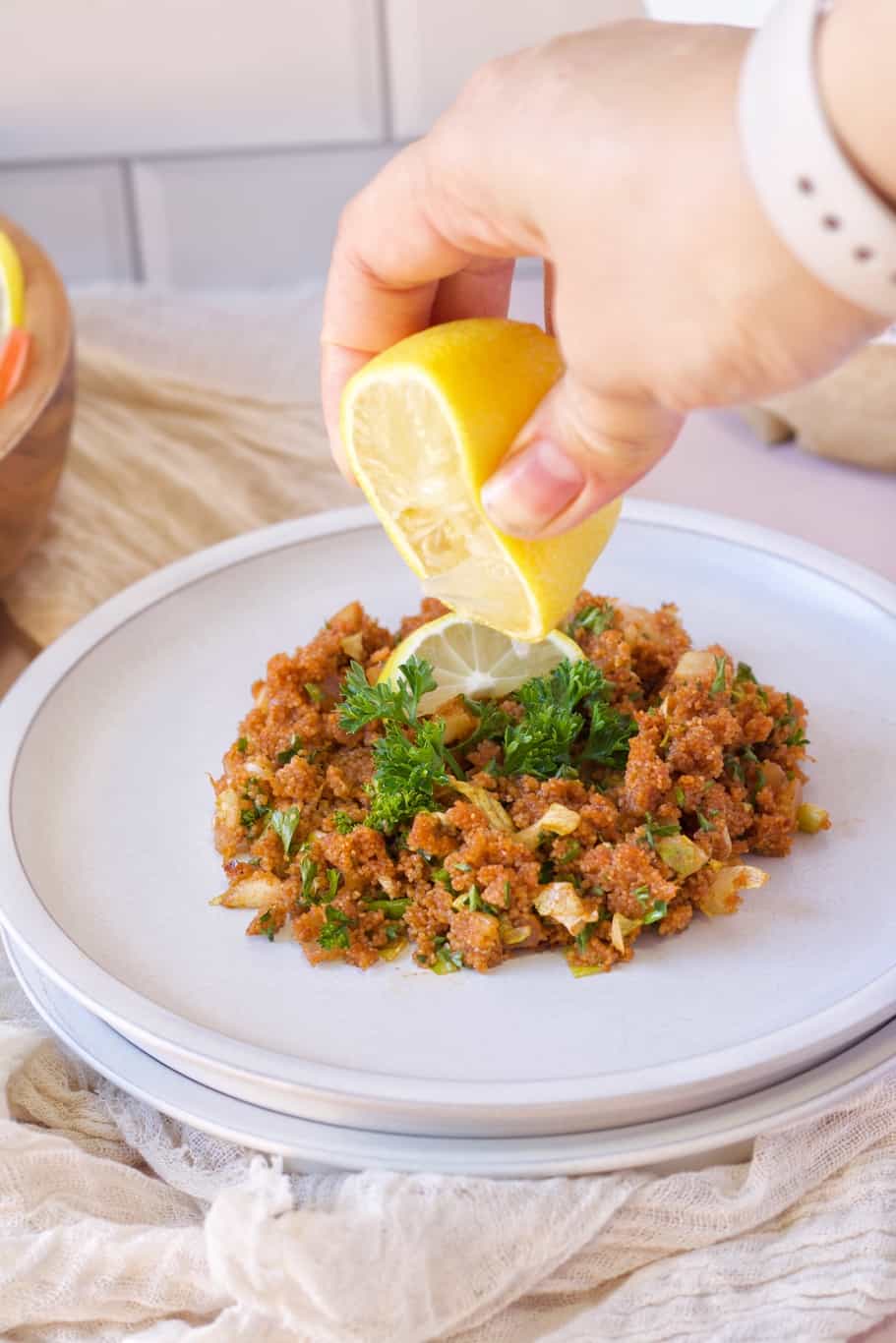 a plate of kisir salad garnished with fresh herbs and drizzled with lemon juice