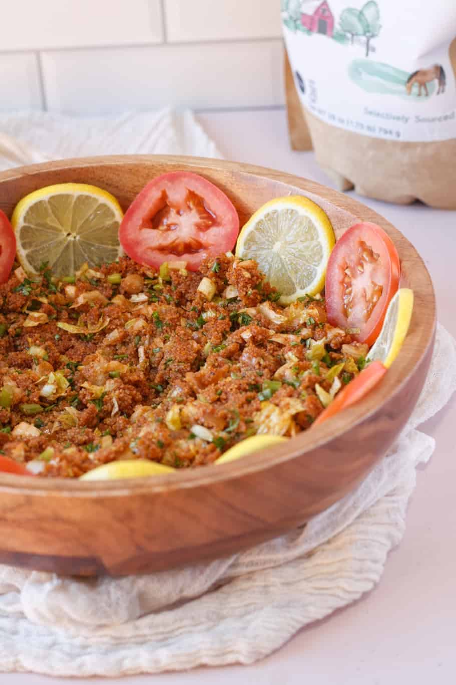 A bowl of Turkish Kisir Salad garnished with lemon and tomato slices.