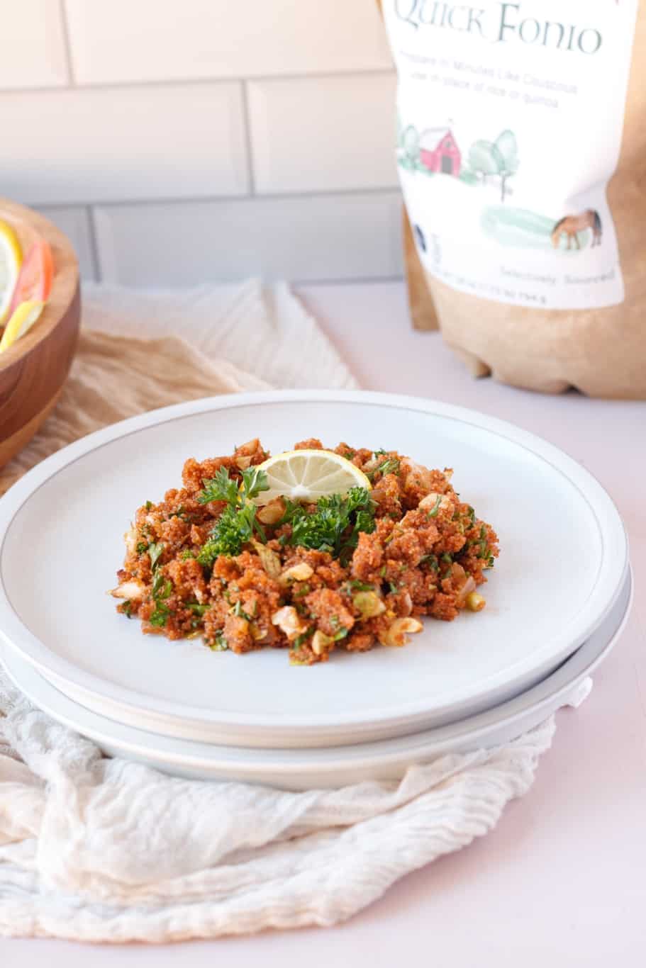 a plate of turkish bulgur salad garnished with a lemon wedge and fresh herbs