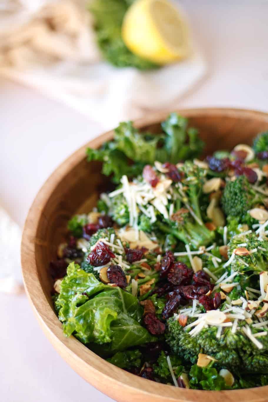 a plate of copycat chick-fil-a’s kale crunch salad topped with maple vinaigrette dressing, dried cranberries, sliced almonds, and parmesan cheese