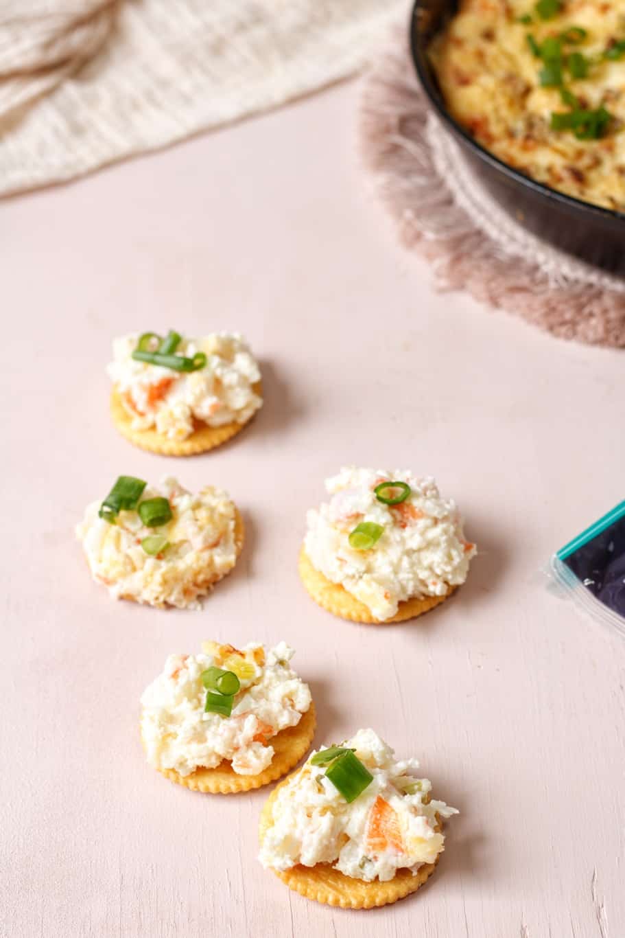Five crackers topped with cream cheese crab dip and garnished with green onions