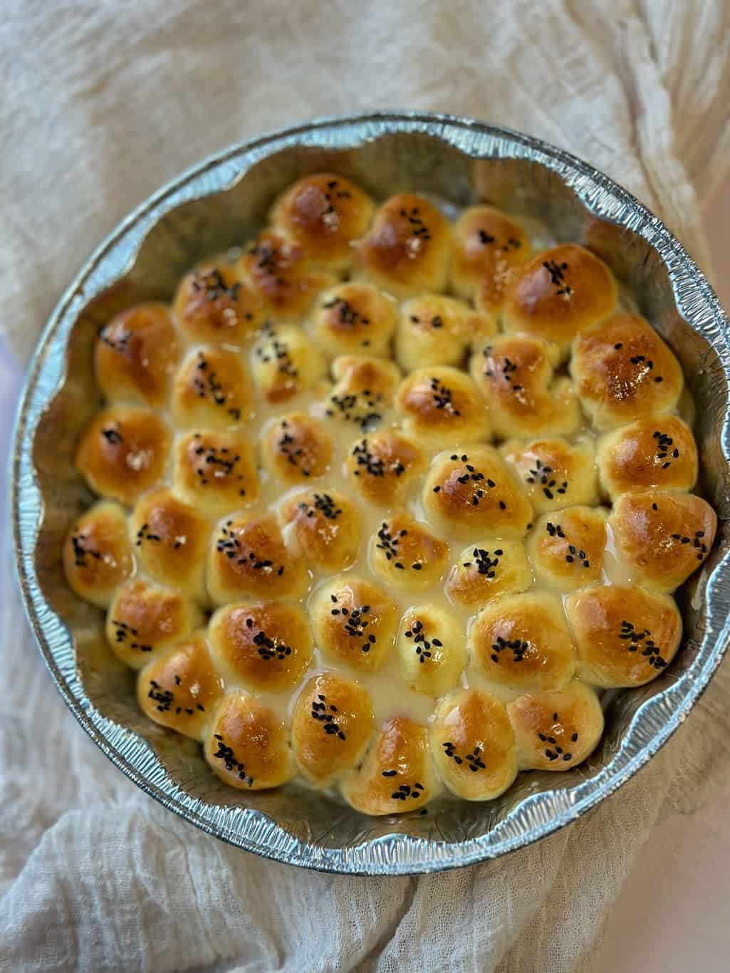 Fluffy bread rolls with cream cheese stuffed inside, arranged in a honeycomb pattern, and drizzled with honey.