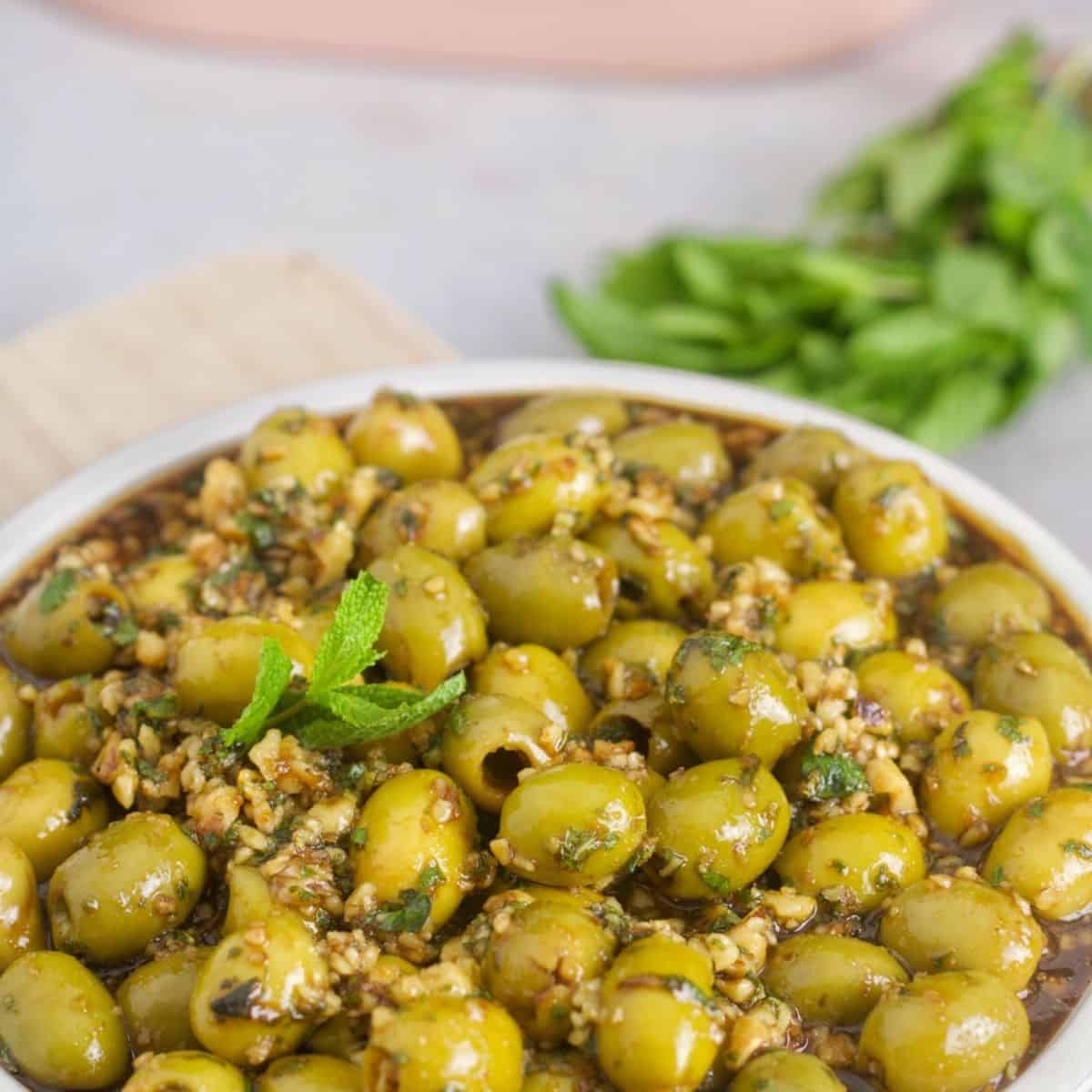 a bowl of Zeytoon Parvardeh appetizer that is wonderfully prepared with pitted green olives, chopped mint, and chopped walnuts
