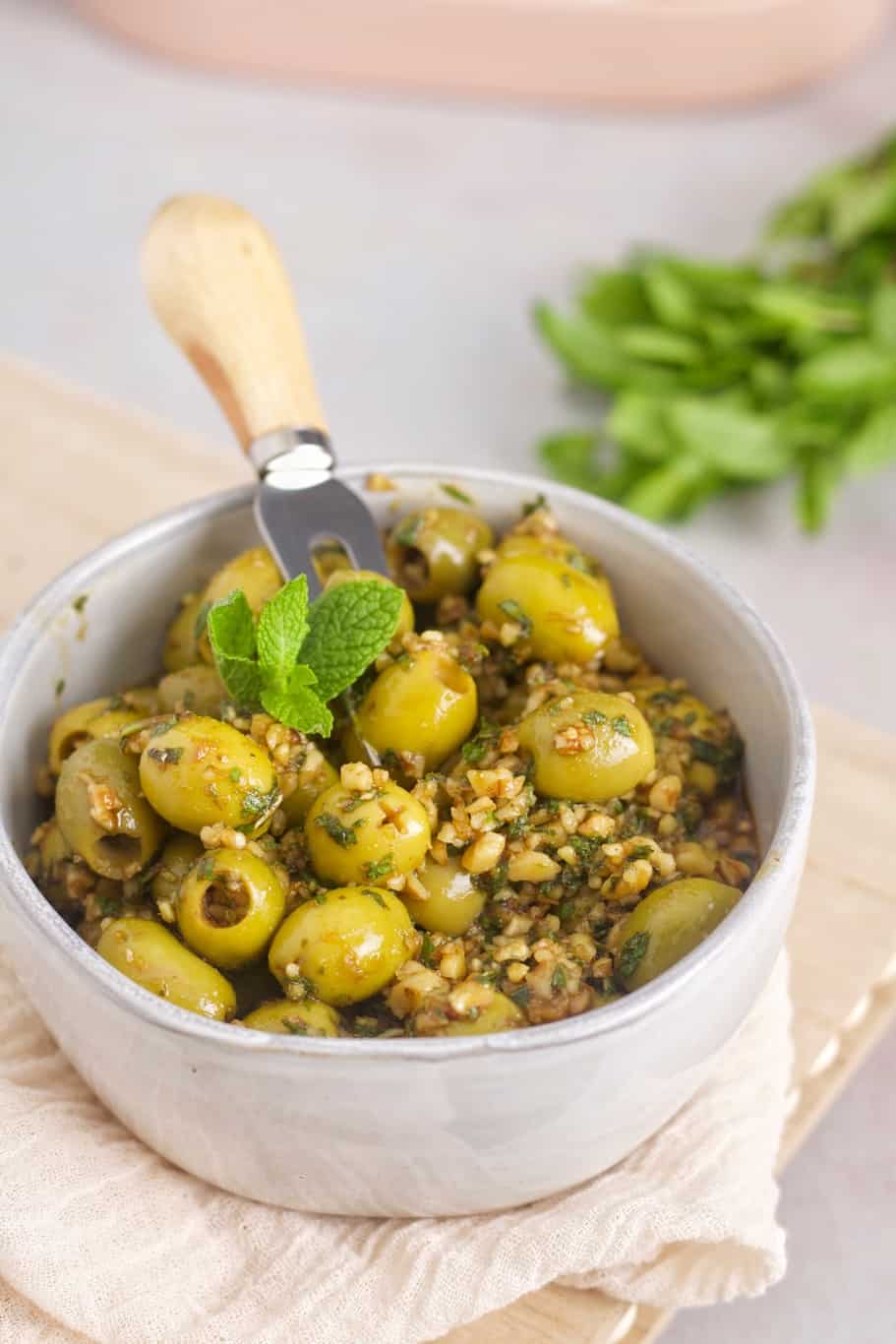 Zeytoon Parvardeh topped with fresh mint leaves and served in a medium white bowl