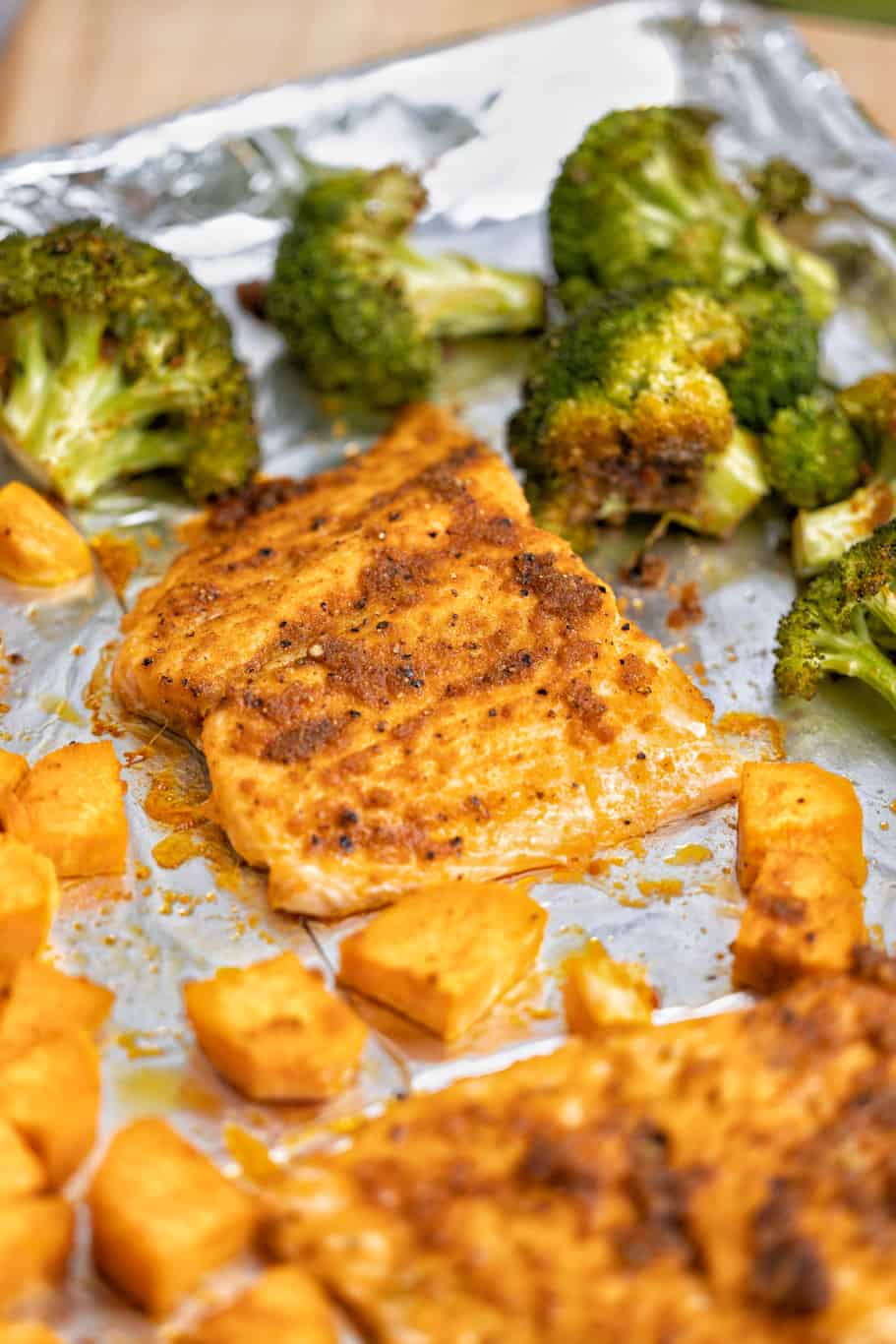 perfectly seasoned salmon filets with sweet potatoes and broccoli on a tray