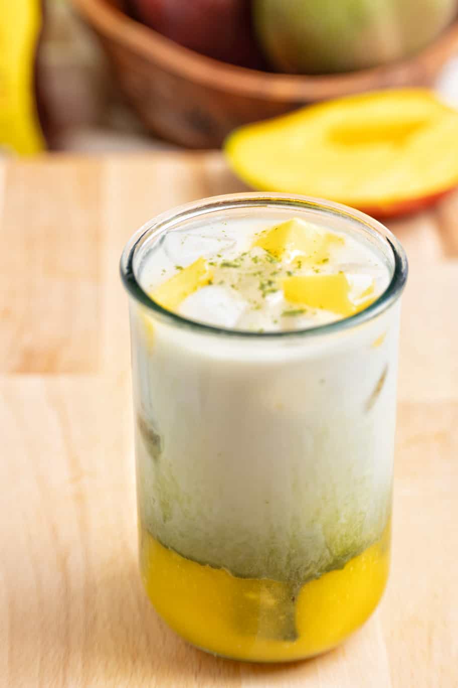 iced mango matcha latte served with mango cubes and a sprinkle of green matcha powder on the top 