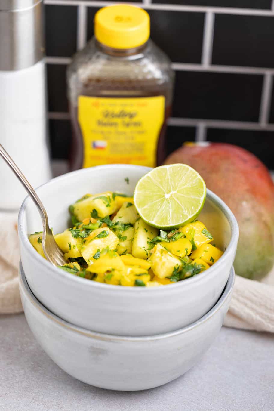 a small bowl of tropical fruit salsa served with fresh lime