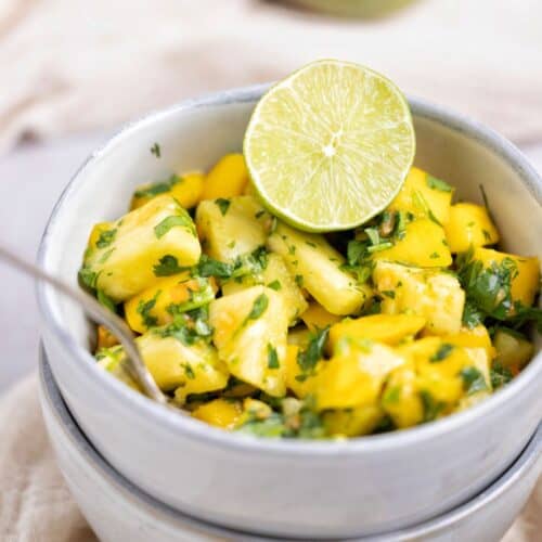 a bowl of pineapple mango salsa served with fresh lime