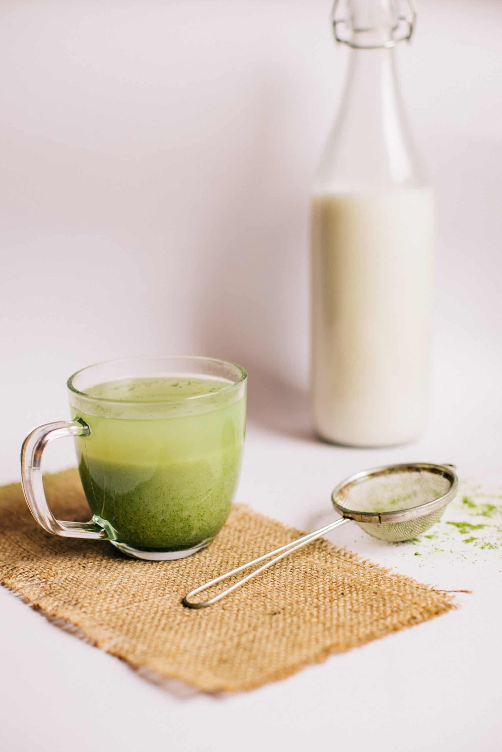 a bowl of milk, matcha tea, and a sieve