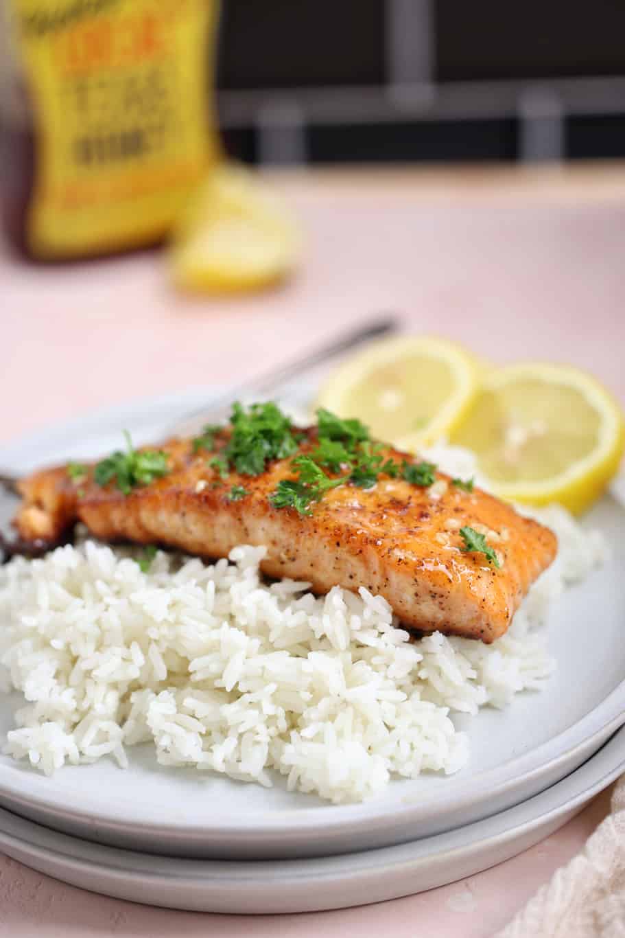 one filet of pan seared salmon garnished with parsley on a bed of white rice