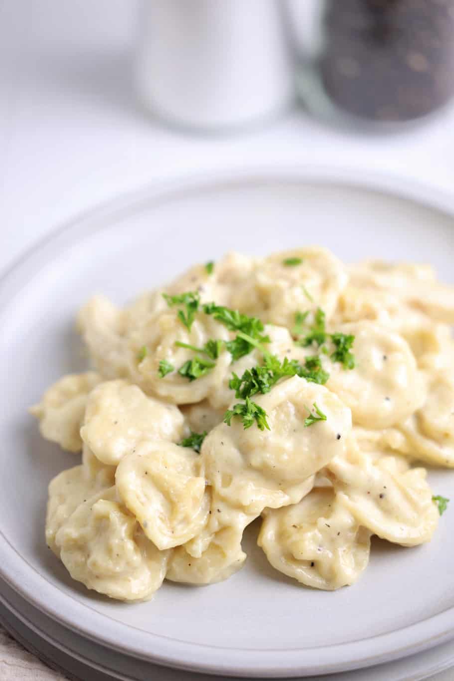 a white plate of panera tortellini alfredo garnished wwith fres parsley